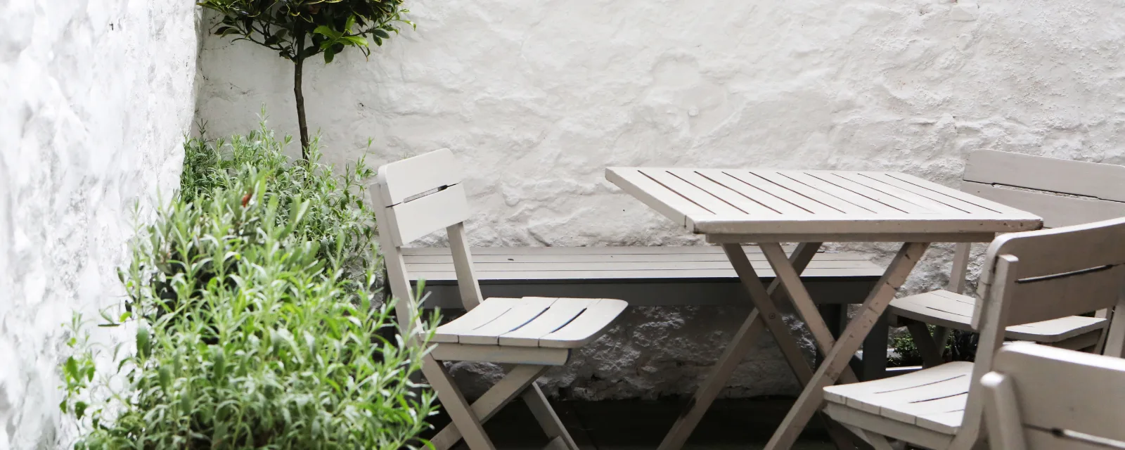 Photo d'illustration, qui ne montre pas cette structure : une petite terrasse à l'ombre, une table et des chaises contre un mur blanc.