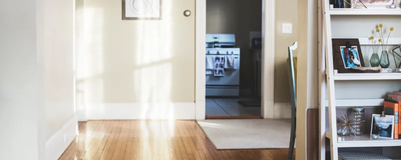Photo d'illustration, qui ne montre pas cette structure : un couloir d'entrée, un parquet au soleil et une étagère.