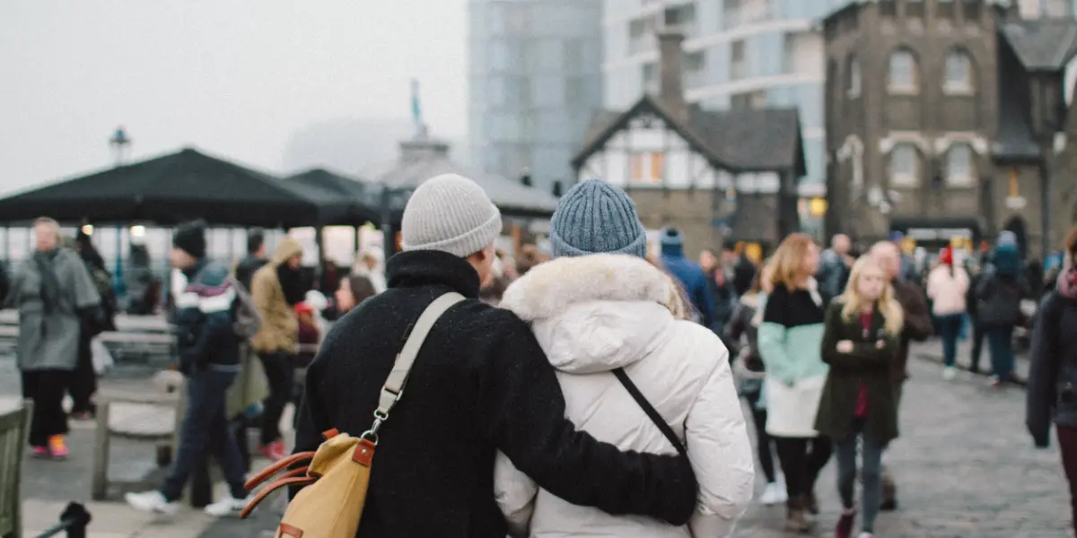 Un jeune couple, de dos, dans une rue passante.